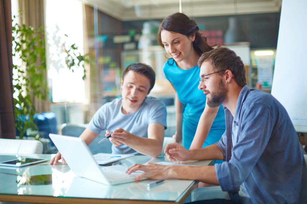 Group of three successful business partners in casual discussing sales at meeting in office