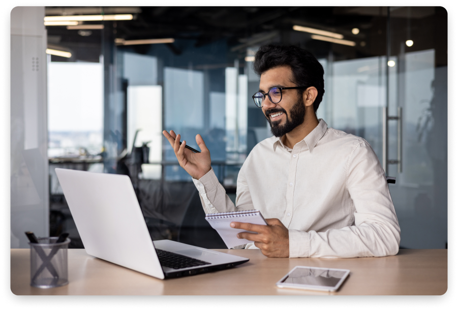 A man sitting at a desk with a laptop in front of him, creating engaging product videos.