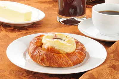 A croissant is sitting on a plate next to a cup of coffee, making it an ideal 101 breakfast option.