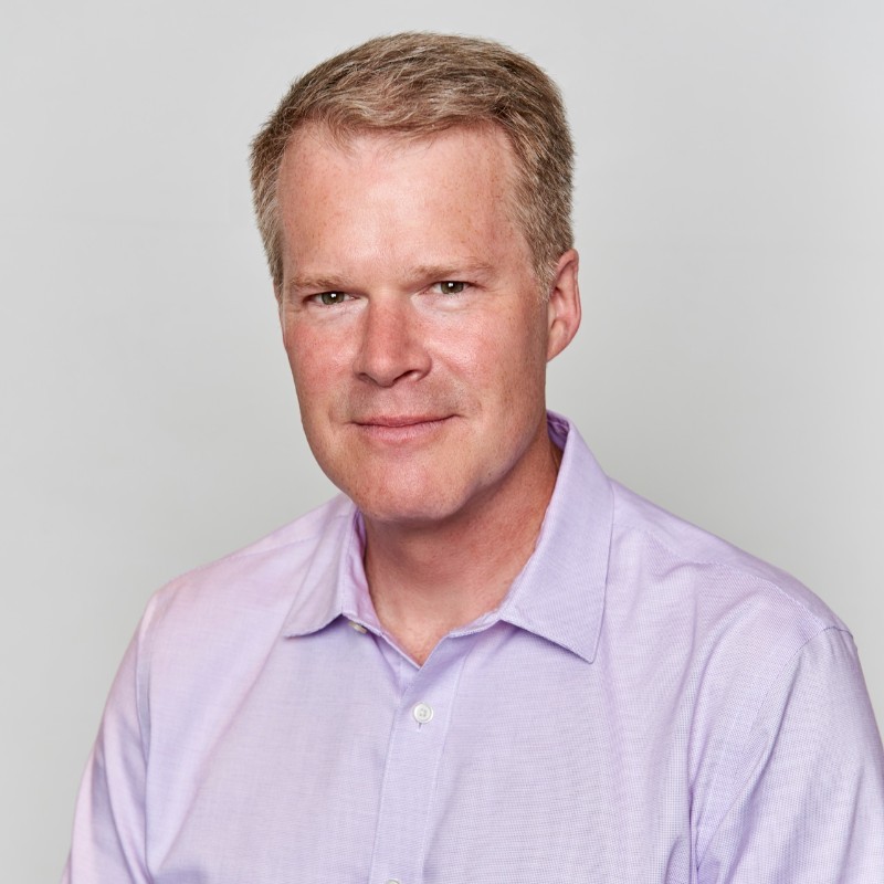 A person with short hair wearing a light purple shirt poses against a plain background. Consensus