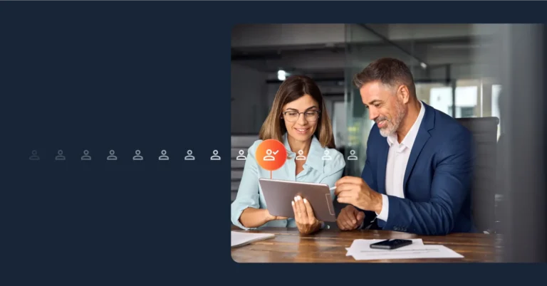 A man and a woman in business attire look at a tablet in an office setting, smiling as they discuss lead qualification strategies together. Consensus