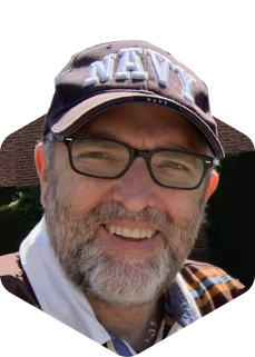 A man wearing glasses and a navy hat.