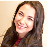 Smiling person with long brown hair, wearing a maroon top and dark jacket, looking upward. Consensus