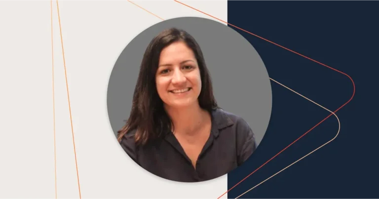 Amanda Bertucci, a woman with long brown hair wearing a dark blouse, smiles against a gray circular background with a minimalist geometric design. She's known for her expertise in hiring Presales and talented SEs.
